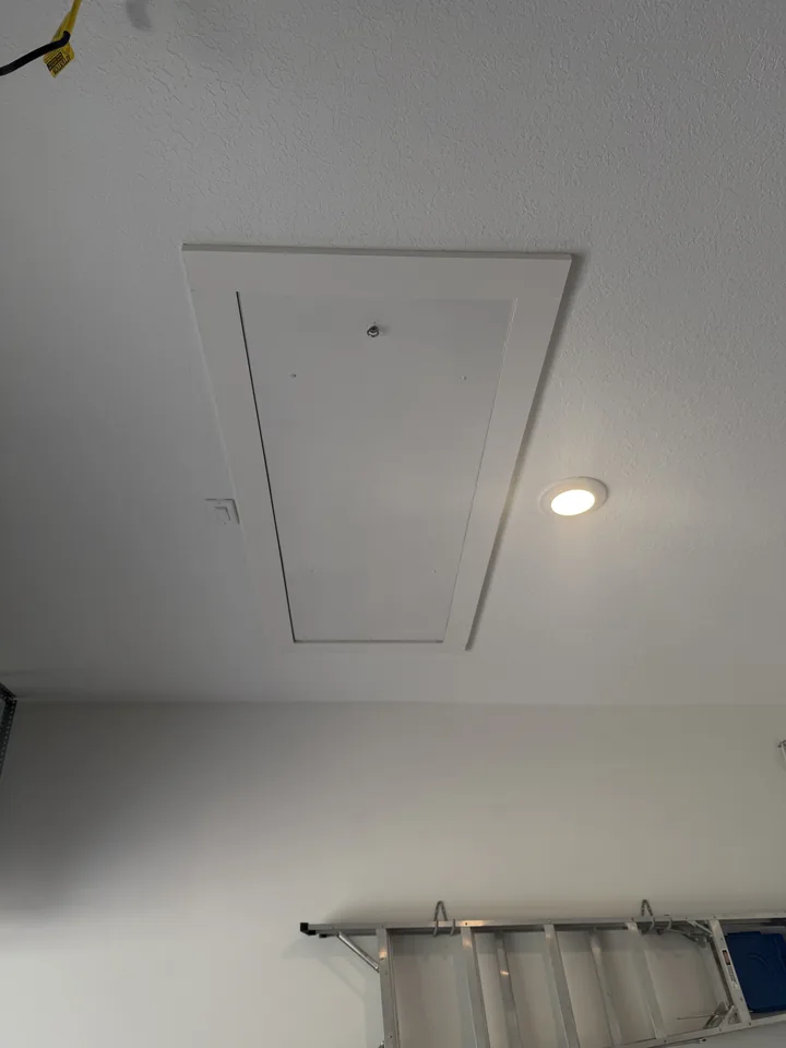 The new attic ladder folded away, its door closed flush inside the white trim of the ceiling opening