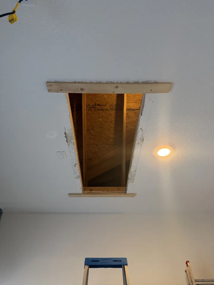 SilverLeaf garage ceiling before: the framed attic opening standing open, with the roof framing visible above