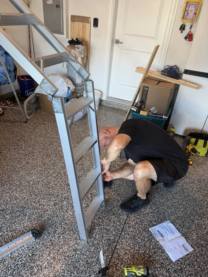 A Garage Wolves installer assembling the aluminum ladder sections on the garage floor
