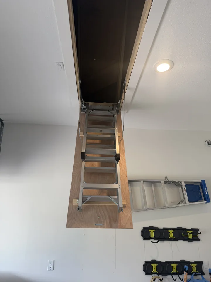 The attic ladder unfolded from the ceiling opening, seen from below