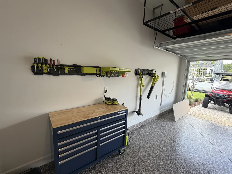 The same SilverLeaf wall after installation, with tool rails holding drills, a blower and hand tools above a rolling workbench