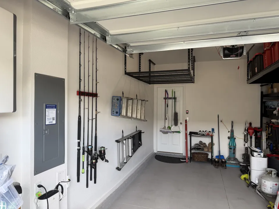 The same SilverLeaf garage after organization, floor completely clear with fishing rods and ladders mounted on the wall and an overhead rack above